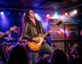 An electric guitar plugged into an amplifier on stage