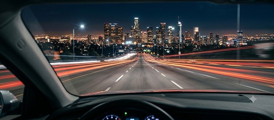 Dashboard view of a car driving through a blurry neon city at night