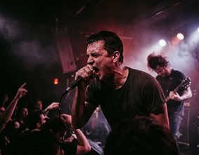A passionate vocalist screaming into a microphone on stage