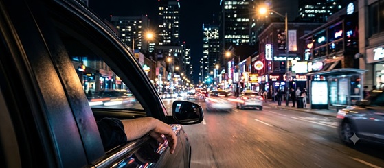 A view from inside a car driving through neon-lit city streets