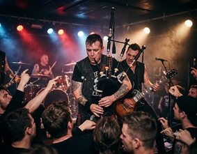 A punk rocker playing an acoustic guitar aggressively on stage