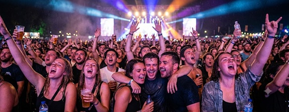 A group of partygoers shouting lyrics with their arms raised