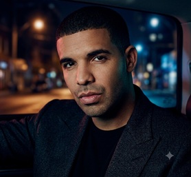 Drake holding a microphone under dramatic spotlighting