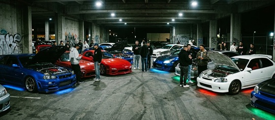 A group of modified cars parked together under streetlights