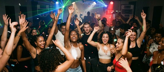A DJ playing rap music to a hyped crowd at a club
