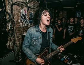 A grunge aesthetic band performing on a small stage