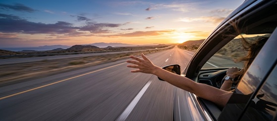 A person wearing sunglasses driving a car on a highway