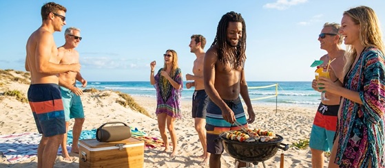 Friends laughing and holding drinks at a summer beach party